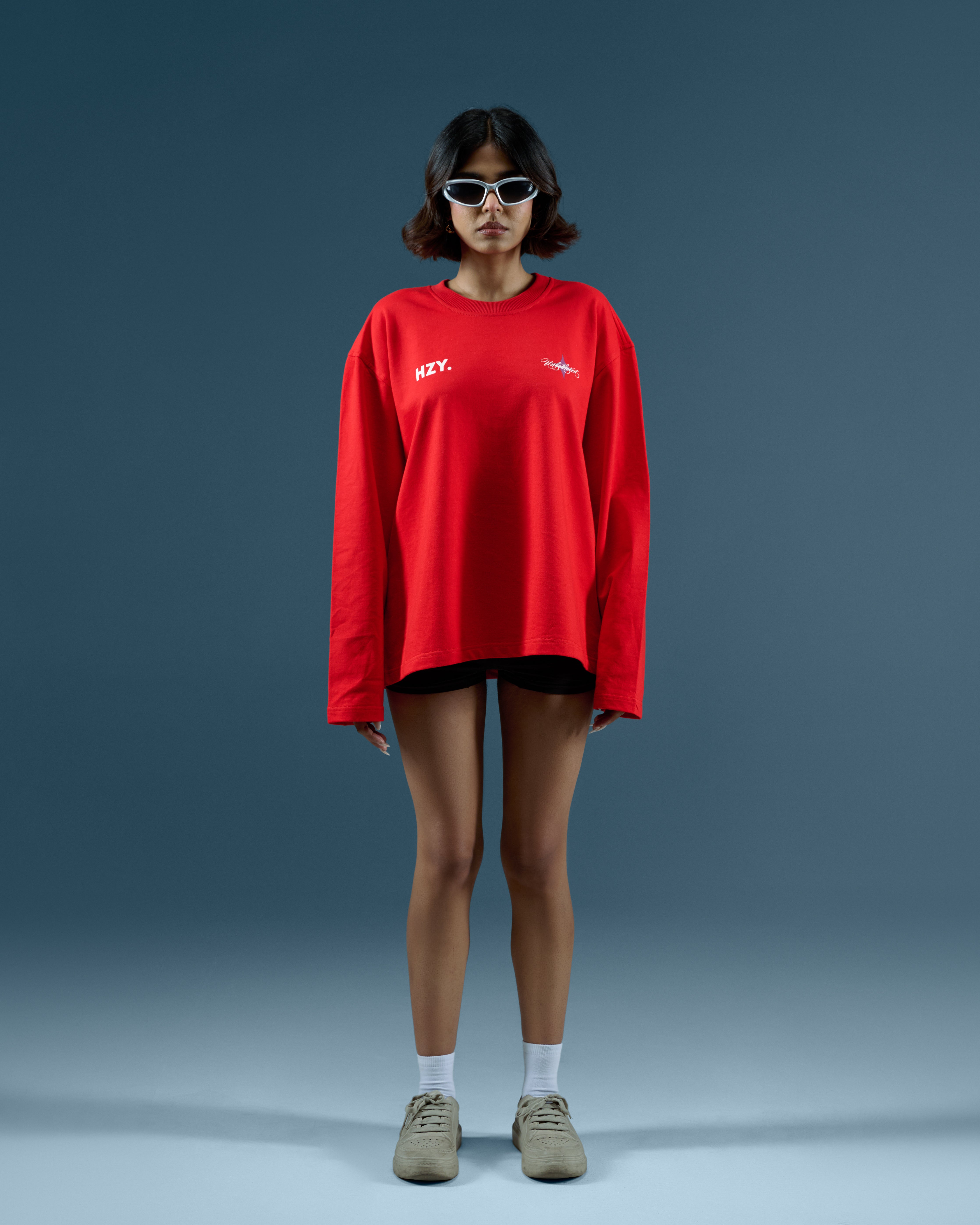 Person wearing a red long-sleeve shirt with visible branding on a gray background